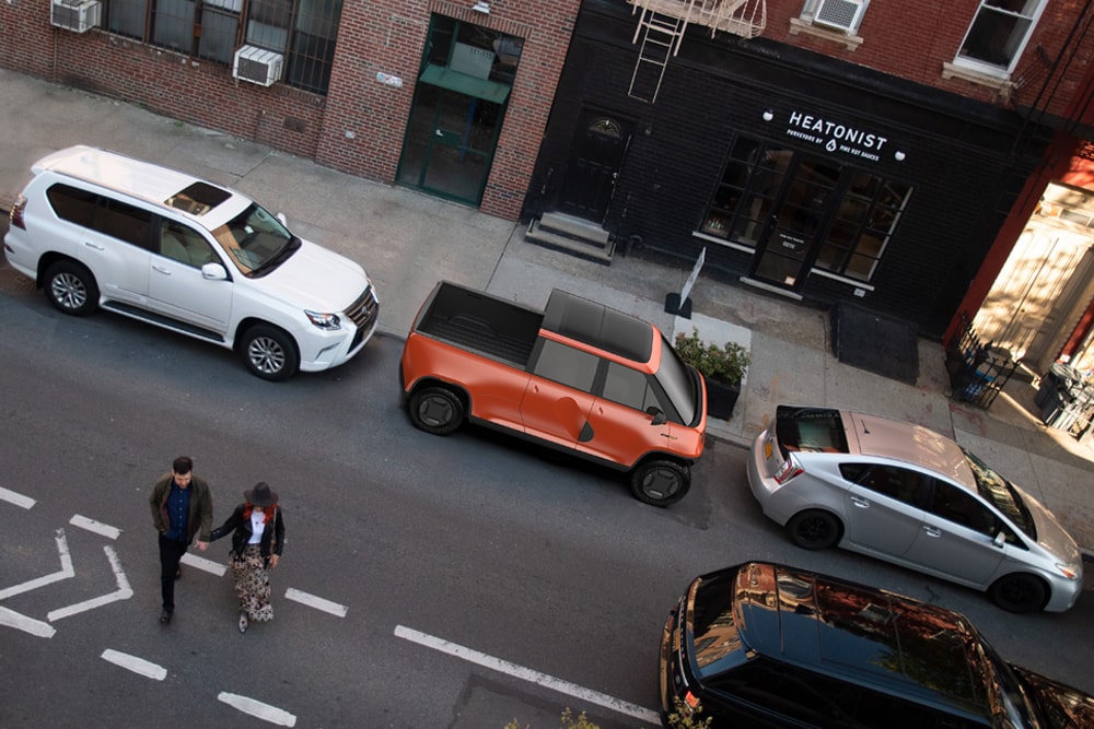 A top down view of a couple walking on a San Francisco street with an orange TELO MT1 behind them tightly parked in between two other cars.